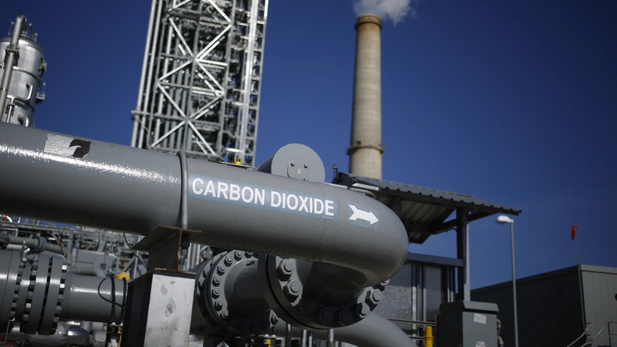 Industrial CO₂ pipeline and storage facility infrastructure under clear blue sky