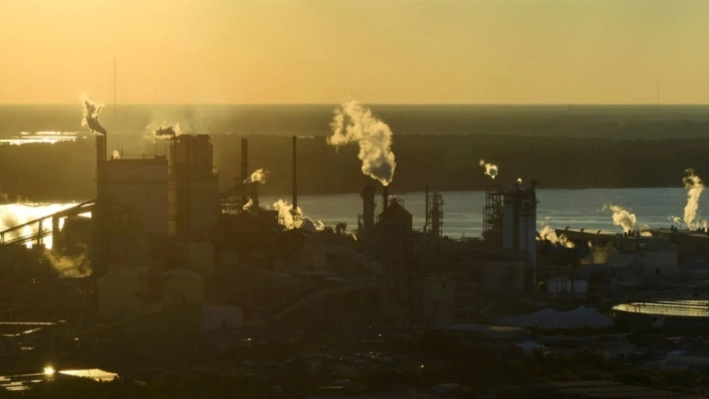 Carbon capture facility with industrial stacks releasing steam at dusk