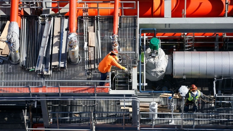 Workers inspecting pipeline equipment on an industrial CO₂ transport facility